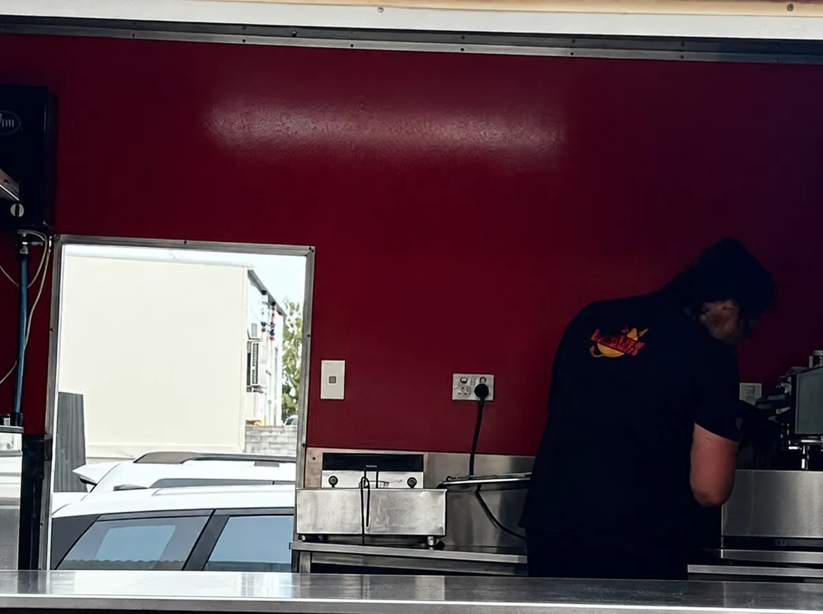 Inside the red trailer, steam rising off the fryer