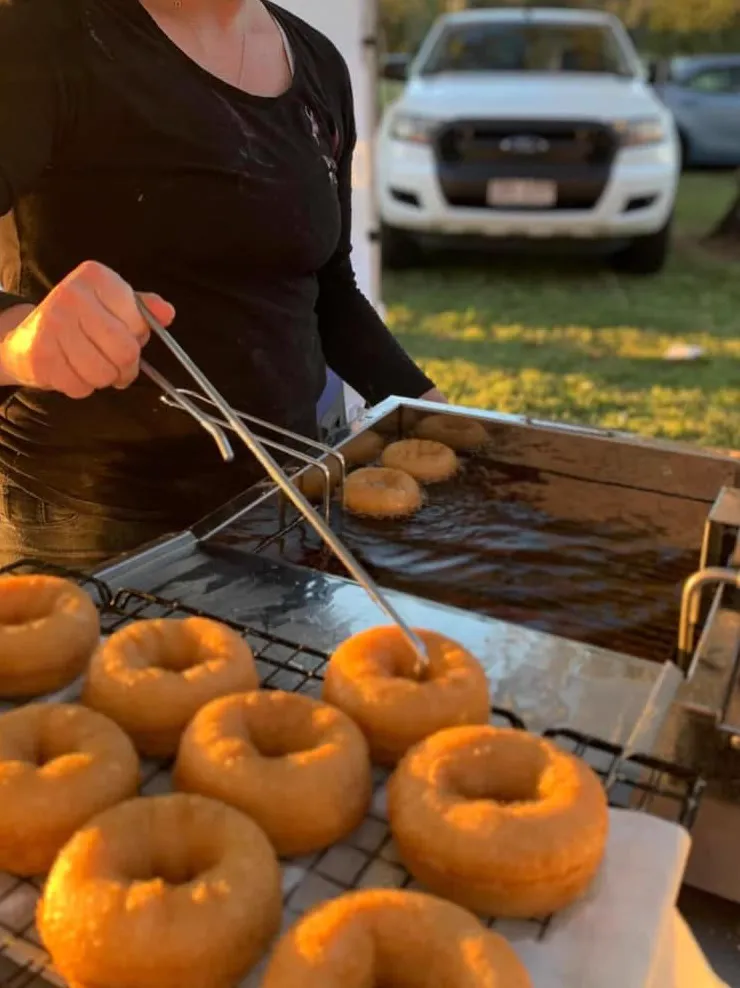Lifting fresh doughnuts out of the fryer at a market at sunset