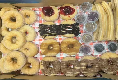 A grazing box of doughnuts, churro pieces and dipping sauces