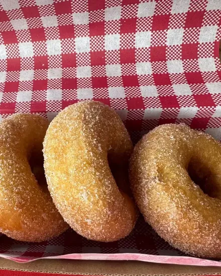 Three cinnamon sugar doughnuts on red check paper